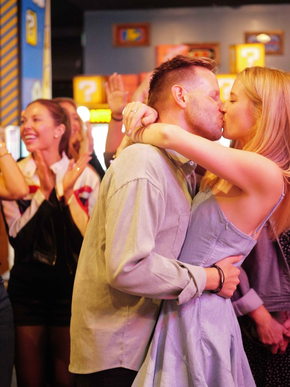 Annie and Serik kissing as friends cheer at Coin-Op